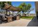 Expansive backyard featuring a covered outdoor kitchen, lush lawn, mature trees, and a playset at 1311 W Ellis St, Mesa, AZ 85201