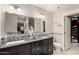 Well-lit bathroom with double sinks, granite counters, decorative tile accents, and a walk-in closet at 1311 W Ellis St, Mesa, AZ 85201
