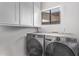 Laundry room showcasing gray front-load washer and dryer with bright white cabinets at 1914 S Brooks Cir, Mesa, AZ 85202