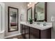 Modern bathroom featuring double sinks, wood cabinets, and decorative mirrors at 2023 W Yellowbird Ln, Phoenix, AZ 85085