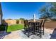 Backyard patio with artificial grass, tall privacy wall, and an outdoor dining set under a clear blue sky at 2023 W Yellowbird Ln, Phoenix, AZ 85085