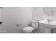 A well lit half bath with a round mirror, pedestal sink, and toilet at 21284 E Camacho Rd, Queen Creek, AZ 85142