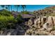 Exterior of luxurious home with desert landscaping, waterfall and a stone bridge pathway at 2233 E Behrend Dr # 162, Phoenix, AZ 85024