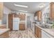 Well-lit kitchen with wood cabinets, white appliances, and wood look flooring at 2233 E Behrend Dr # 162, Phoenix, AZ 85024