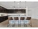 Modern kitchen with an island that includes seating, stainless steel appliances and sleek, dark wood cabinetry at 22938 E Calle Luna --, Queen Creek, AZ 85142