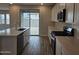 Modern kitchen features white cabinetry, stainless appliances and sliding glass doors to the backyard at 3390 S 180Th Ln, Goodyear, AZ 85338