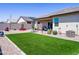 Spacious backyard with artificial grass, desert landscaping, and a covered patio at 37008 N Aleutian Dr, San Tan Valley, AZ 85143
