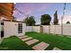 Charming backyard with lush artificial turf, stepping stone pathway, storage shed, and secure privacy fence at 4613 S Rita Ln, Tempe, AZ 85282