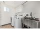 Bright laundry room features modern washer, dryer, stainless steel sink, and white cabinets at 554 N Sunset Dr, Chandler, AZ 85225