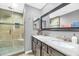 Bathroom with a double sink vanity, granite countertop, dark cabinets, and a glass enclosed shower at 5612 E Emile Zola Ave, Scottsdale, AZ 85254