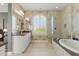 Bathroom boasts a double vanity, soaking tub, and glass shower with ample natural light from a large window at 7122 W Ivanhoe St, Chandler, AZ 85226