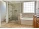 Bathroom features a glass shower, tub, tile walls, and a vanity sink at 7419 S 45Th Ave, Laveen, AZ 85339