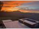 Backyard view featuring a pool, hot tub, putting green, and a beautiful sunset over the mountains at 8396 E Granite Pass Rd, Scottsdale, AZ 85266