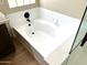 Modern white bathtub with tile surround, modern black faucet, and wood-look floor at 9109 W Watson Ln, Peoria, AZ 85381
