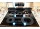 Close-up of a sleek, black glass stovetop with circular burner patterns and stainless steel trim at 9109 W Watson Ln, Peoria, AZ 85381
