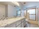 Bathroom with granite countertop, modern fixtures, and a glass-enclosed shower and bathtub at 9814 W Menadota Dr, Peoria, AZ 85382