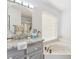 Bright bathroom features a vanity with a granite countertop, a large mirror, and a luxurious soaking tub by the window at 9814 W Menadota Dr, Peoria, AZ 85382