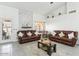 Bright living room featuring vaulted ceilings, a marble accent wall, and two comfortable leather couches at 9814 W Menadota Dr, Peoria, AZ 85382