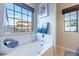 Bright bathroom features a soaking tub, tiled floors, and a view out of the window at 13318 W Indianola Ave, Litchfield Park, AZ 85340