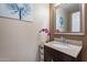 Stylish powder room features a granite countertop, decorative mirror, and modern fixtures at 13318 W Indianola Ave, Litchfield Park, AZ 85340