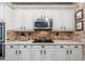 Close-up of a stylish kitchen features white cabinets, stainless appliances, and brick backsplash at 15240 N Clubgate Dr # 160, Scottsdale, AZ 85254