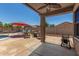 Inviting backyard area featuring patio seating, a red umbrella, a sparkling pool, and well-maintained landscaping at 16219 W Yucatan Dr, Surprise, AZ 85379