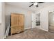 Cozy bedroom features neutral walls, carpet, ceiling fan, mirrored closet, and a classic wood armoire at 16219 W Yucatan Dr, Surprise, AZ 85379