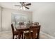 Cozy dining room with a wood table and chairs, a ceiling fan, and a large window providing natural light at 16219 W Yucatan Dr, Surprise, AZ 85379