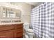 Bathroom with wood vanity, granite countertop, decorative mirror, a toilet, and a walk-in shower at 1733 W Surrey Ave, Phoenix, AZ 85029