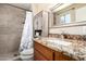 Bathroom features a tiled shower, a sink with vanity, decorative mirror, and a toilet at 1733 W Surrey Ave, Phoenix, AZ 85029