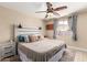 This bedroom has a ceiling fan, light walls, wood flooring, a window with curtains, and a cozy bed at 1733 W Surrey Ave, Phoenix, AZ 85029
