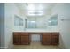 Bathroom featuring a long vanity with wood cabinets, double mirrors, and modern lighting at 17433 W Holland Ln, Surprise, AZ 85388