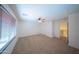 Bonus room with blinds on a window, a ceiling fan, neutral carpet, and access to the upstairs creates a versatile space at 17433 W Holland Ln, Surprise, AZ 85388