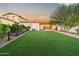 A large backyard with artificial turf, desert landscaping, and a covered patio at 17706 N Rosa Dr, Maricopa, AZ 85138
