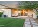 Spacious backyard featuring lush artificial turf, patio, seating, and desert landscaping at 17706 N Rosa Dr, Maricopa, AZ 85138