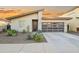 Stylish single-story home featuring desert landscaping, a modern garage door, and a neutral color palette against a vibrant sunset sky at 17706 N Rosa Dr, Maricopa, AZ 85138
