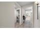 Inviting hallway with neutral walls and tile flooring, leading to a bedroom and a living area filled with natural light at 17706 N Rosa Dr, Maricopa, AZ 85138
