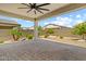 The back patio features pavers, a ceiling fan, and minimal landscaping at 18032 W Muirwood Dr, Goodyear, AZ 85338