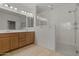Modern bathroom featuring dual sinks, wooden cabinetry, and a glass-enclosed shower at 18032 W Muirwood Dr, Goodyear, AZ 85338