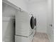Modern laundry room with front-loading washer and dryer units, plus built in shelf at 18032 W Muirwood Dr, Goodyear, AZ 85338