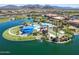 Aerial view of pool and lake with lush desert landscaping and clubhouse nearby at 18032 W Muirwood Dr, Goodyear, AZ 85338