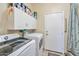 Laundry room featuring front load washer and dryer with white cabinets for storage and access door at 18118 N Smith Dr, Maricopa, AZ 85139