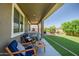 Enjoy outdoor living on this covered patio overlooking the lush backyard with artificial turf and relaxing seating at 26141 N 133Rd Ave, Peoria, AZ 85383