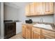 Well-lit laundry room features wooden cabinetry, granite countertops, stainless steel sink and modern washer and dryer at 307 W Piute Ave, Phoenix, AZ 85027