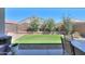View of the backyard, featuring a patch of synthetic grass, gravel, and multiple flowering bushes at 41004 W Crane Dr, Maricopa, AZ 85138