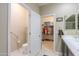 Well-lit bathroom with a toilet, a single sink, and a walk-in closet at 41004 W Crane Dr, Maricopa, AZ 85138