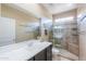 Bathroom with a large mirror, white vanity, glass-enclosed shower with mosaic floors, and tile accents at 41004 W Crane Dr, Maricopa, AZ 85138