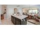 View of the kitchen island with a white countertop and dark cabinets, open to the living room at 41004 W Crane Dr, Maricopa, AZ 85138