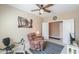 Comfortable living room features a cozy chair, ceiling fan, wall art, and a sleek media center at 41004 W Crane Dr, Maricopa, AZ 85138