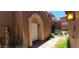 Charming front entrance with an arched entryway, white door, brick pathway, and desert landscaping at 5640 E Bell Rd # 1047, Scottsdale, AZ 85254